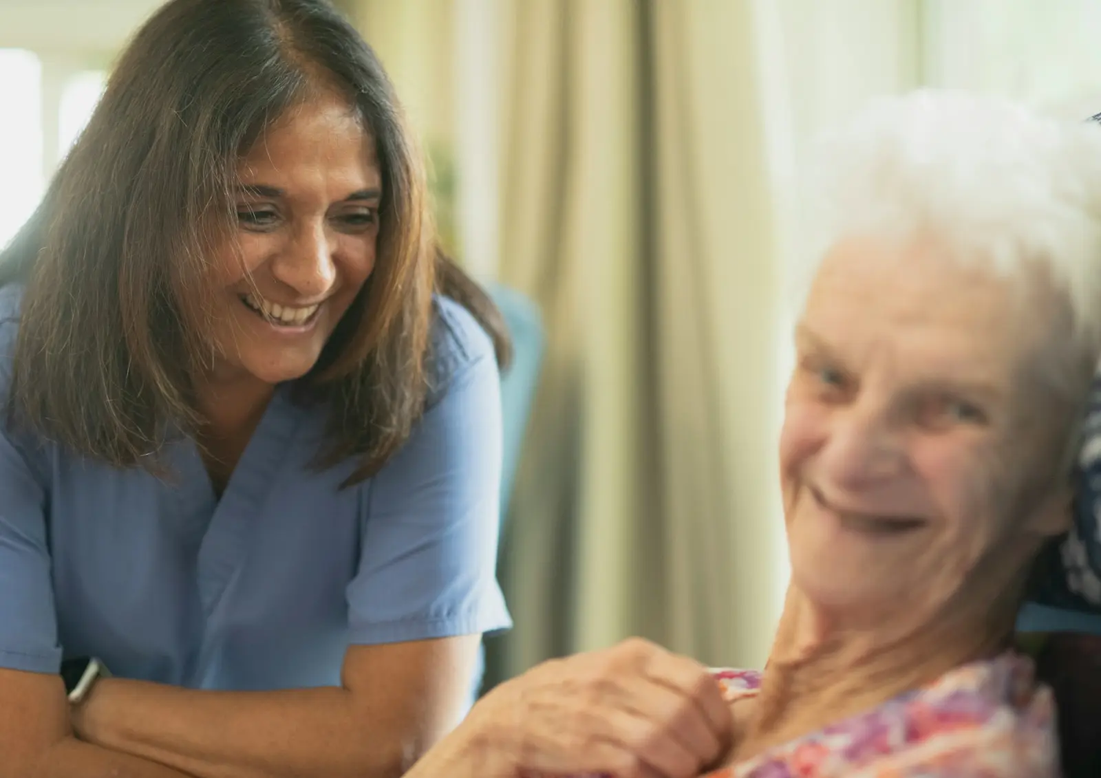 Nurse in scrubs smiling with an older woman