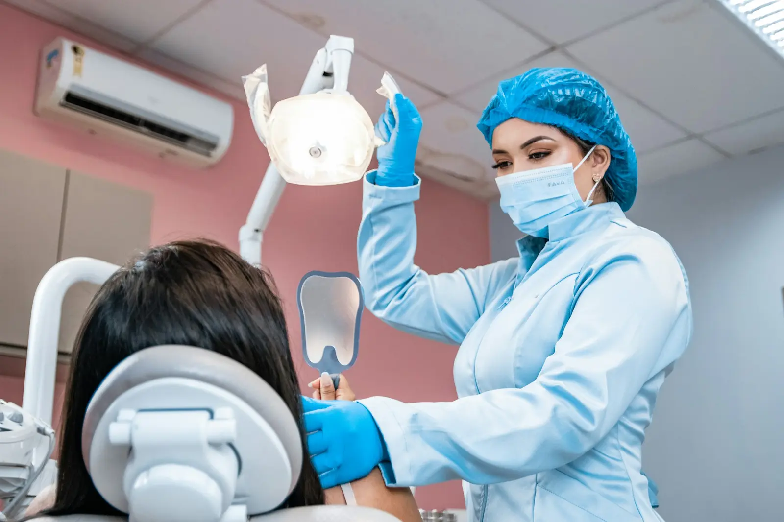 Dental assistant in a mask, hair cover and gloves preparing equipment