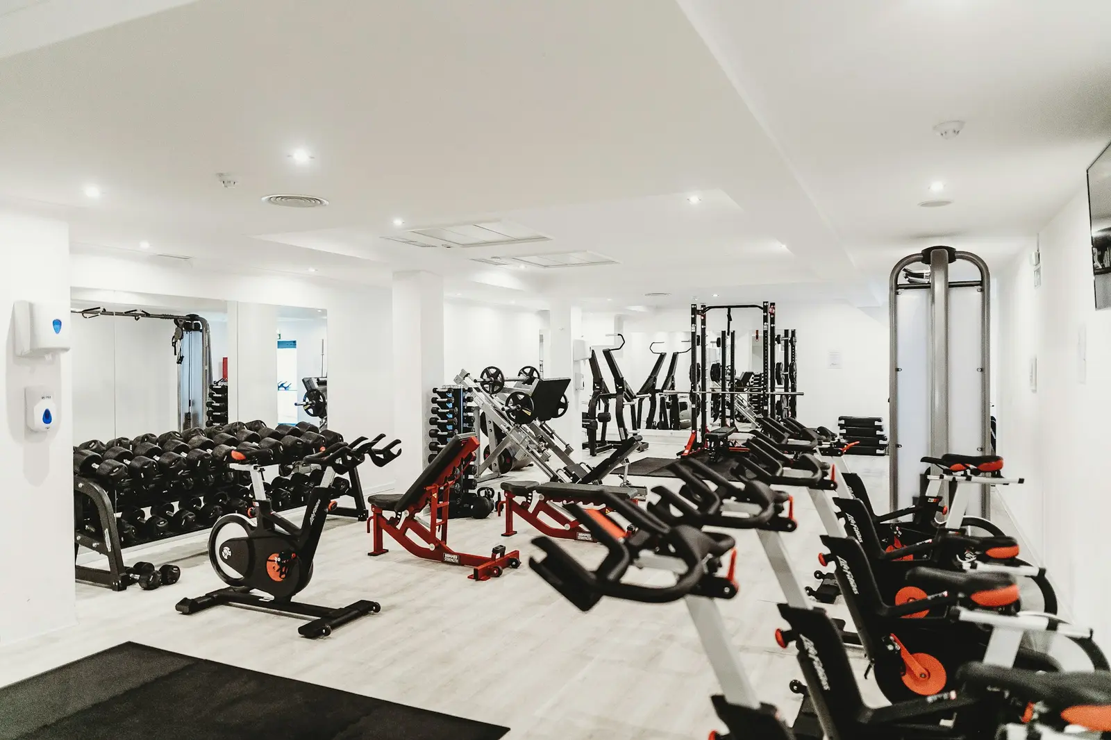 Bright gym with rows of exercise bikes and weight equipment