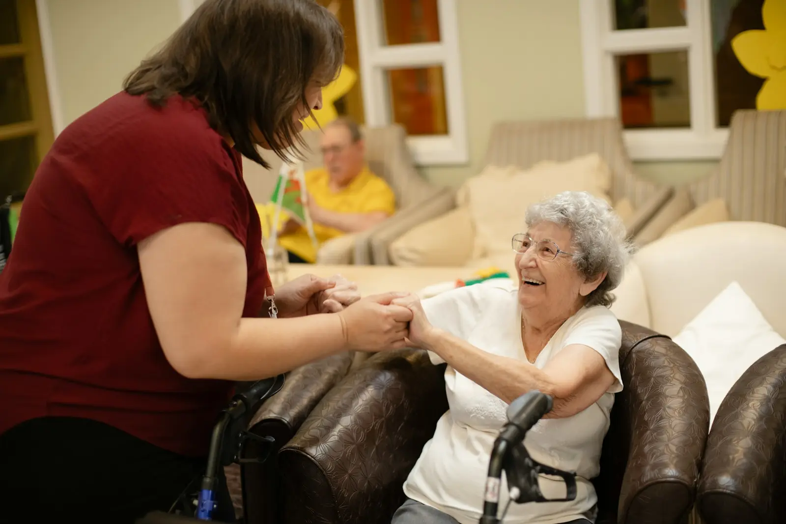 Care worker helping an older woman walk with a frame at home