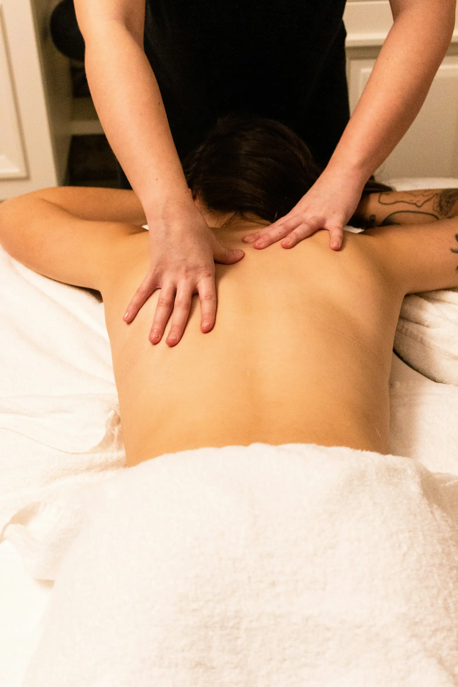 Massage therapist's hands working on a client's back on a towel