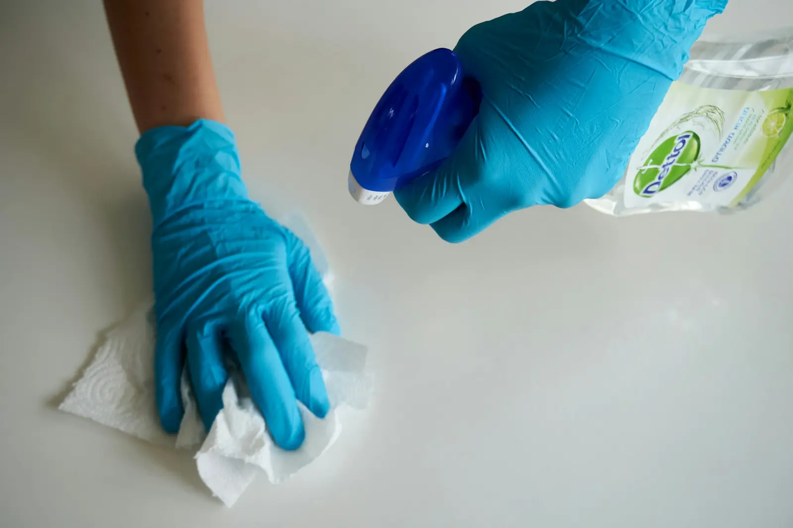 Gloved hand wiping a spill with paper towel