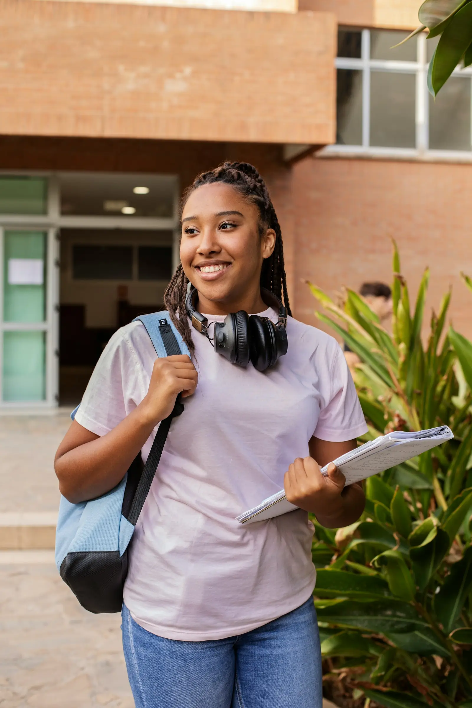 Smiling student holding notebooks on campus