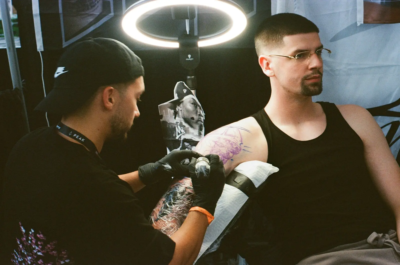 Tattoo artist in black gloves tattooing a client's arm in a studio
